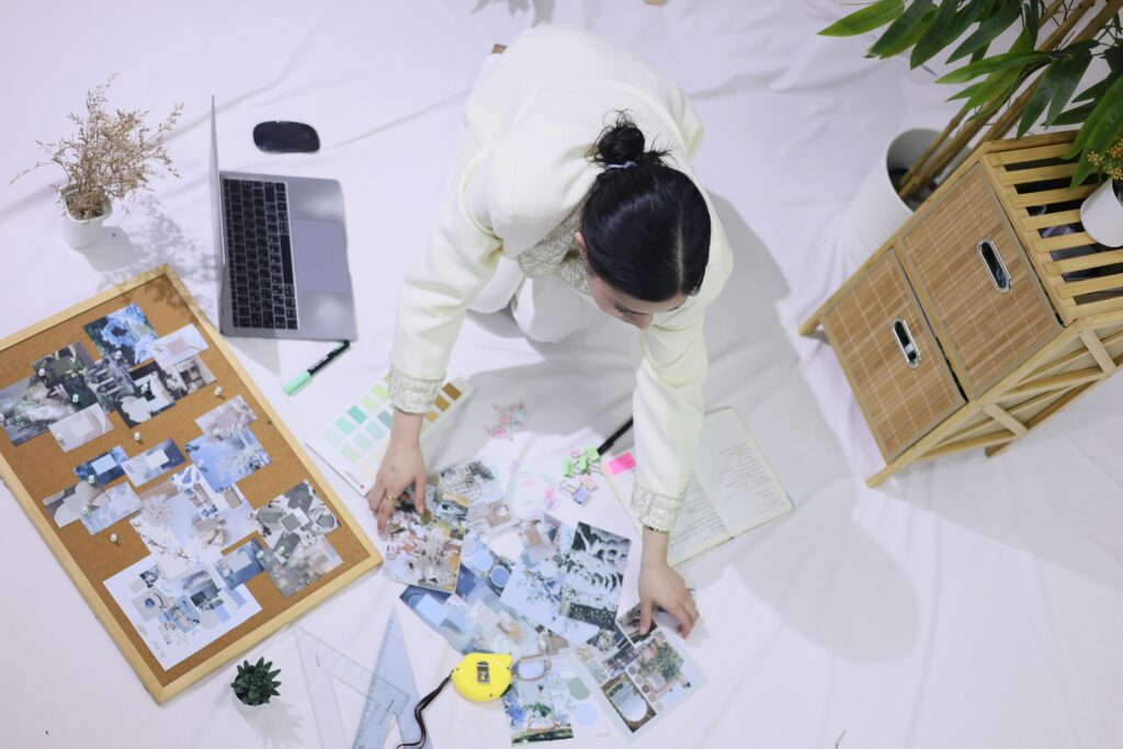 Overhead view of a person working in a creative space with a mood board, planner, and laptop.